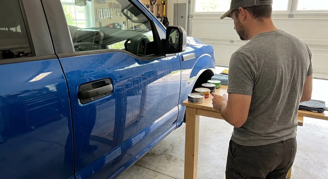 Longest-Lasting Car Wax (Durability Ranked) — car wax product and a foam applicator on deep glossy reflective car paint