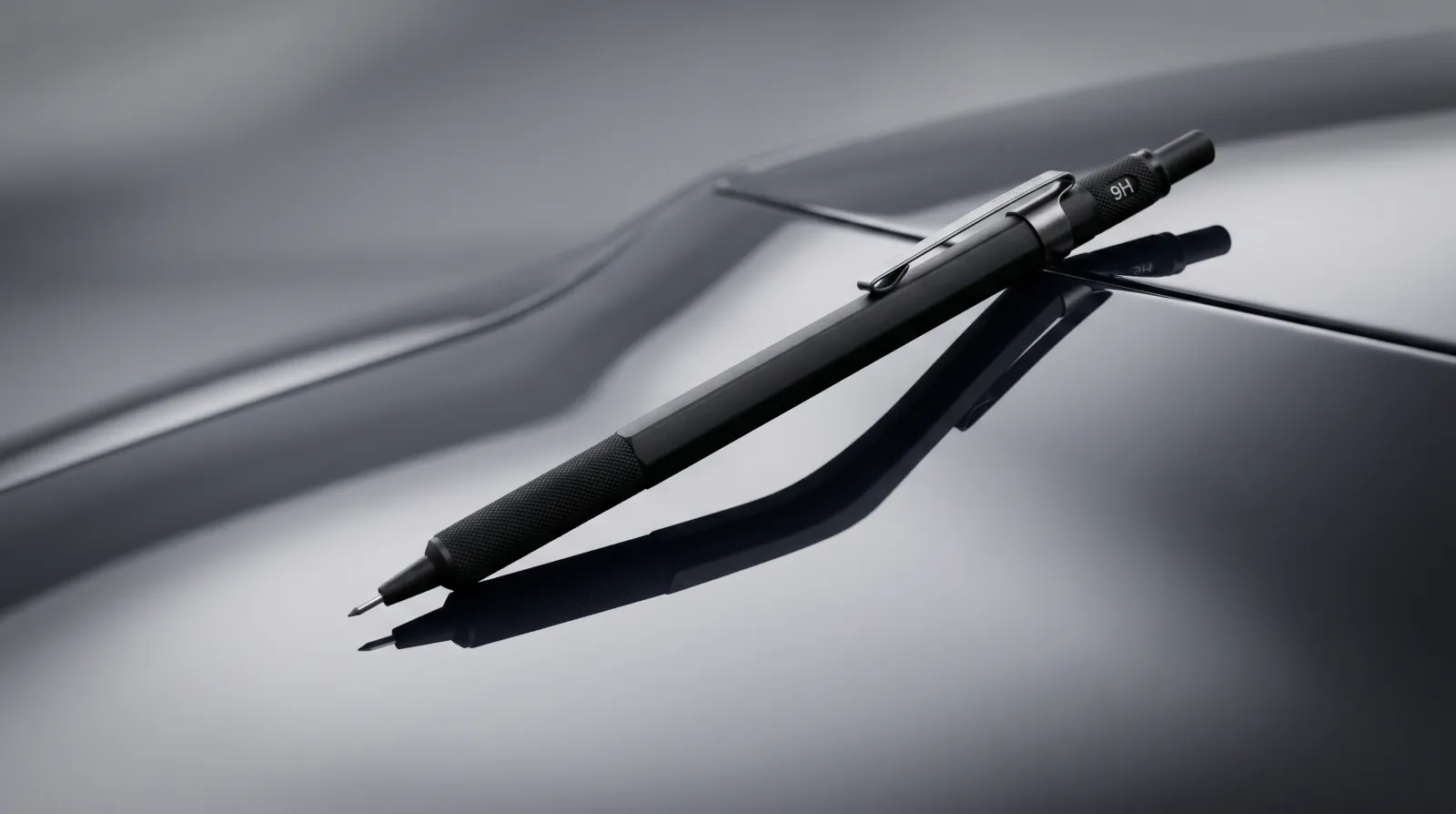 A 9H drafting pencil resting at 45 degrees against a glossy dark-grey car panel