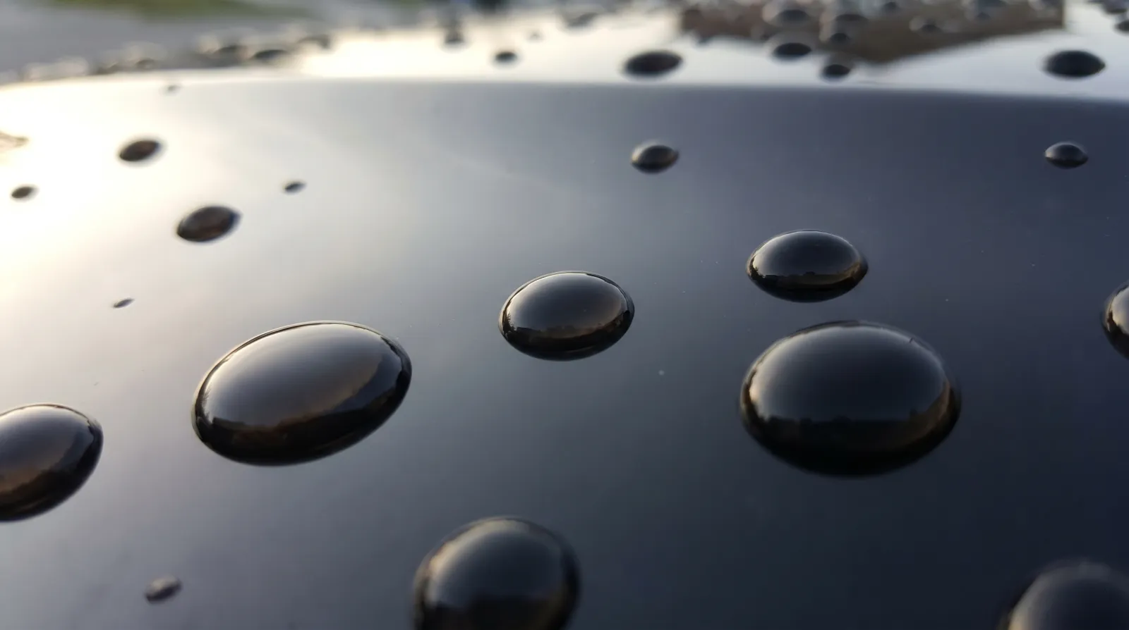Near-perfect spherical water beads on a deep obsidian-black ceramic-coated car panel