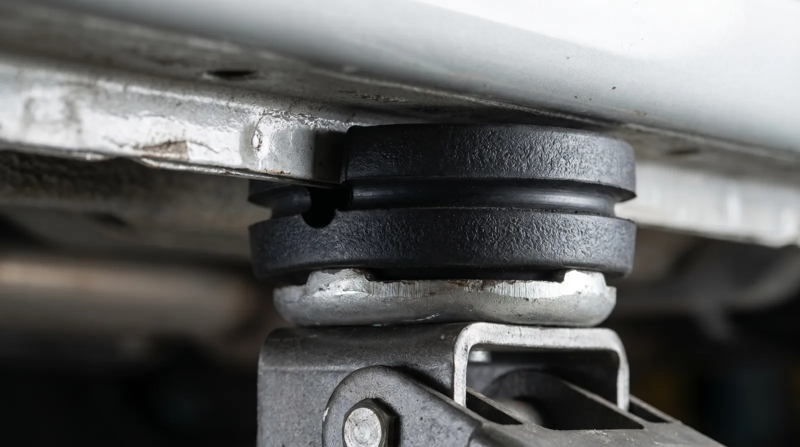 Close-up of a rubber pinch weld adapter puck seated on a floor jack saddle under a car sill