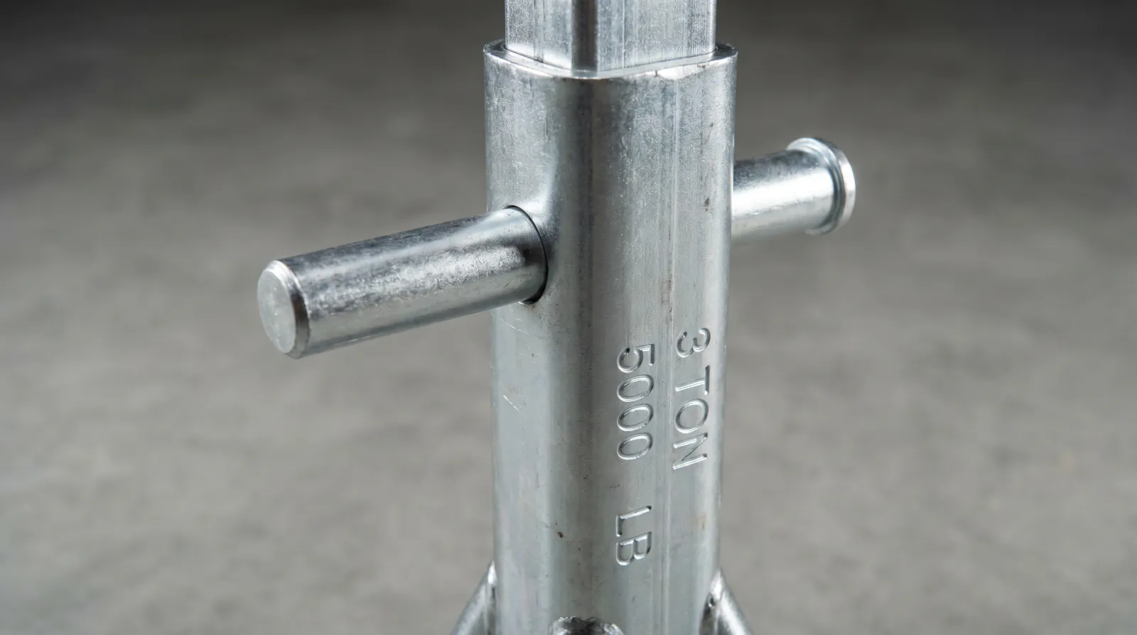 Close-up of a pin-type axle stand showing the through-pin inserted in the post hole with capacity markings on the column