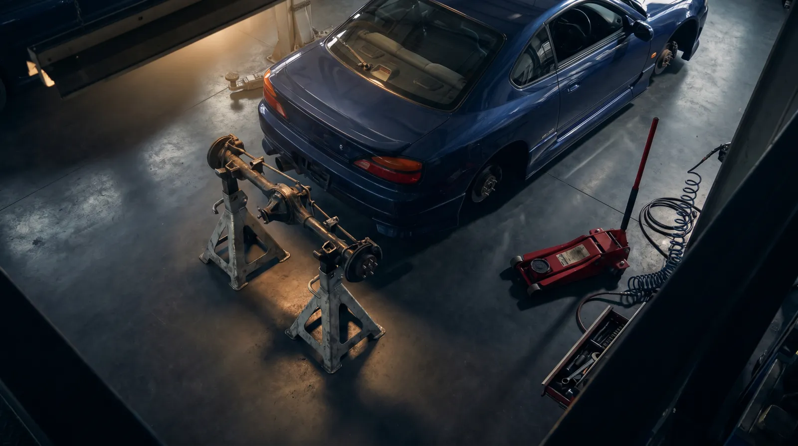 A pair of heavy-duty steel axle stands supporting the rear of a JDM coupe on clean concrete