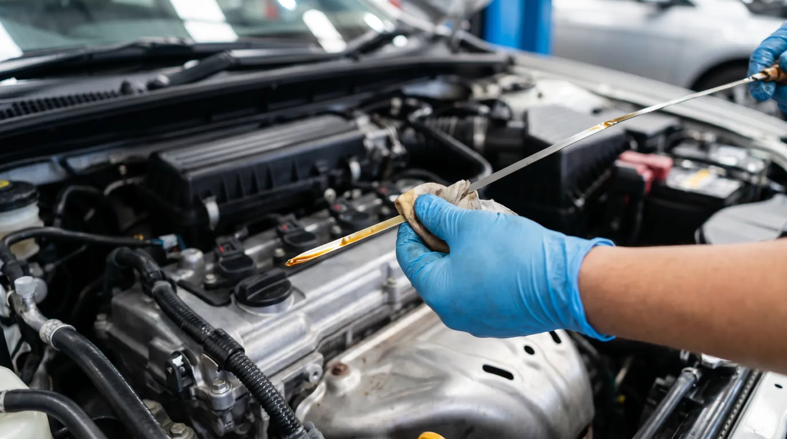 A hand pulling a clean engine dipstick from a JDM inline-four engine bay with golden oil on the tip