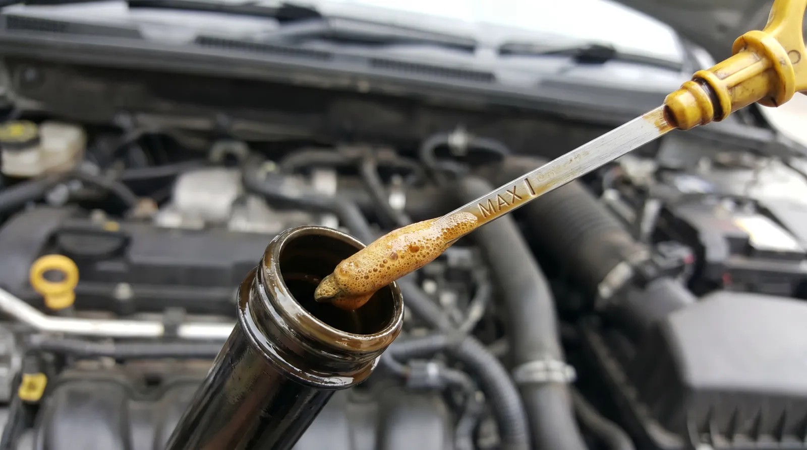 Frothy aerated oil clinging to a dipstick, showing an overfill