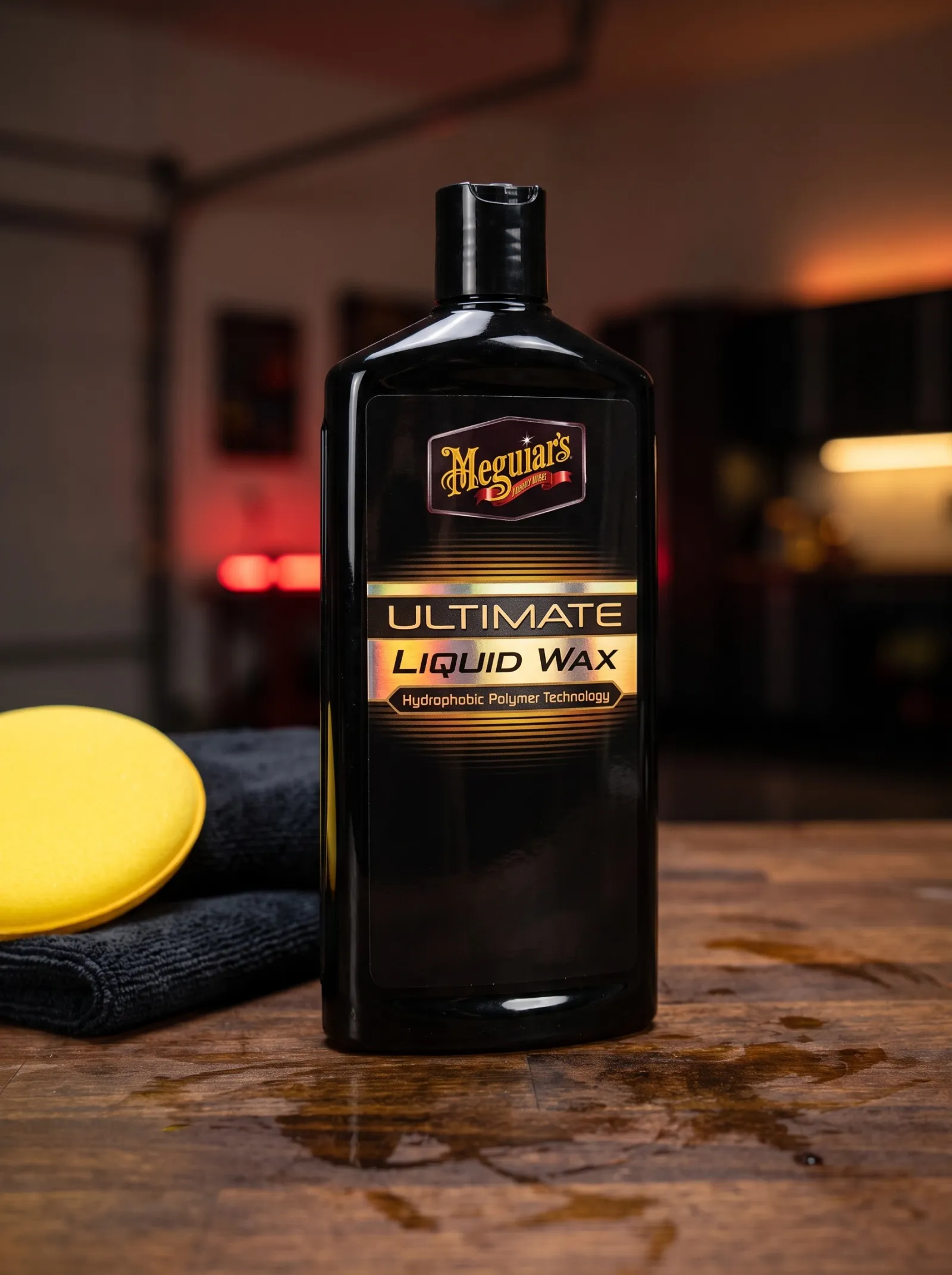 A bottle of liquid car wax on a workbench, representing the wax side of the wax versus ceramic coating decision